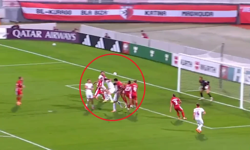 Gol Roberta Lewandowskiego na Malcie Zawodnicy dwóch drużyn piłkarskich walczą o piłkę głową w polu karnym, bramkarz przygotowuje się do interwencji, otaczają ich inni gracze skupieni na sytuacji pod bramką.