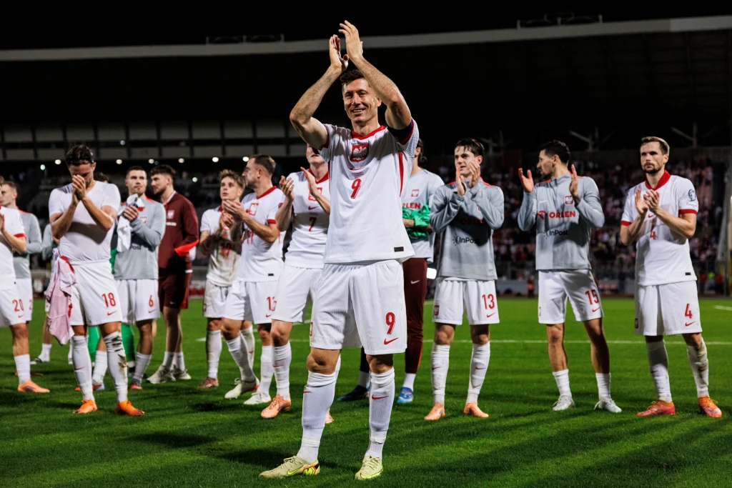 Robert Lewandowski, 17.11.2025 r. Piłkarze reprezentacji Polski w białych strojach, ustawieni na murawie stadionu, biją brawo i dziękują kibicom po meczu.