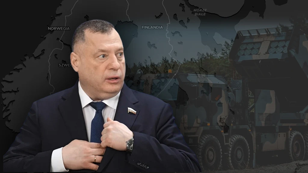 Deputowany Jurij Szwytkin o ćwiczeniach NATO w Finlandii Mężczyzna w garniturze z przypiętą odznaką na tle mapy przedstawiającej Skandynawię oraz pojazdy wojskowe po prawej stronie kadru.