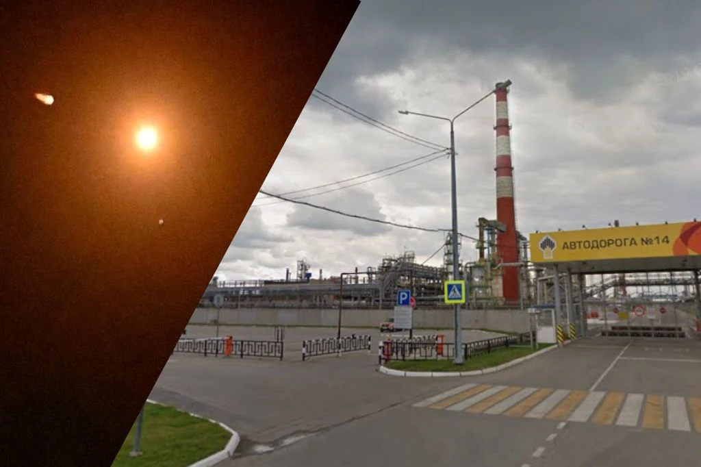 Po lewej stronie jasny błysk światła na ciemnym tle, natomiast po prawej przemysłowy kompleks z wysokim kominem, szarą zabudową i bramą wjazdową oznaczoną numerem 14 oraz rosyjskim napisem.