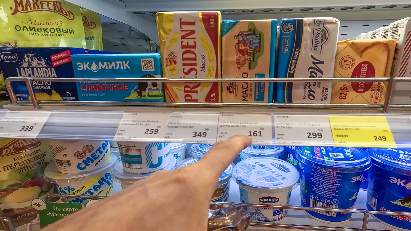 Polak pojechał do Rosji. Zobaczył ceny w sklepach i złapał się za głowę Półka sklepu spożywczego z różnymi opakowaniami masła i produktów mlecznych, na pierwszym planie widoczny palec wskazujący na jedną z cen, liczne marki i ceny wyraźnie widoczne na etykietach.
