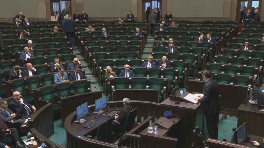 Radosław Sikorski przemawia w Sejmie Sala obrad z rozproszonymi posłami siedzącymi w ławach, osoba przemawiająca przy mównicy, przed nią kilka komputerów i mikrofonów, większość miejsc pozostaje pusta.