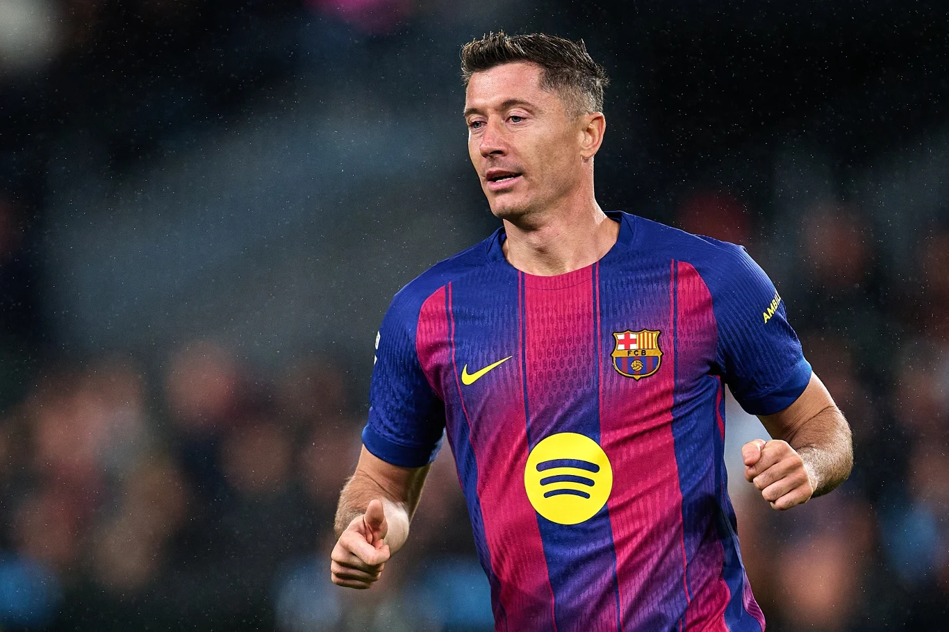 Robert Lewandowski Piłkarz w stroju FC Barcelony w trakcie meczu, z wyraźnym logotypem sponsora na koszulce i skupionym wyrazem twarzy, w tle rozmyte trybuny.