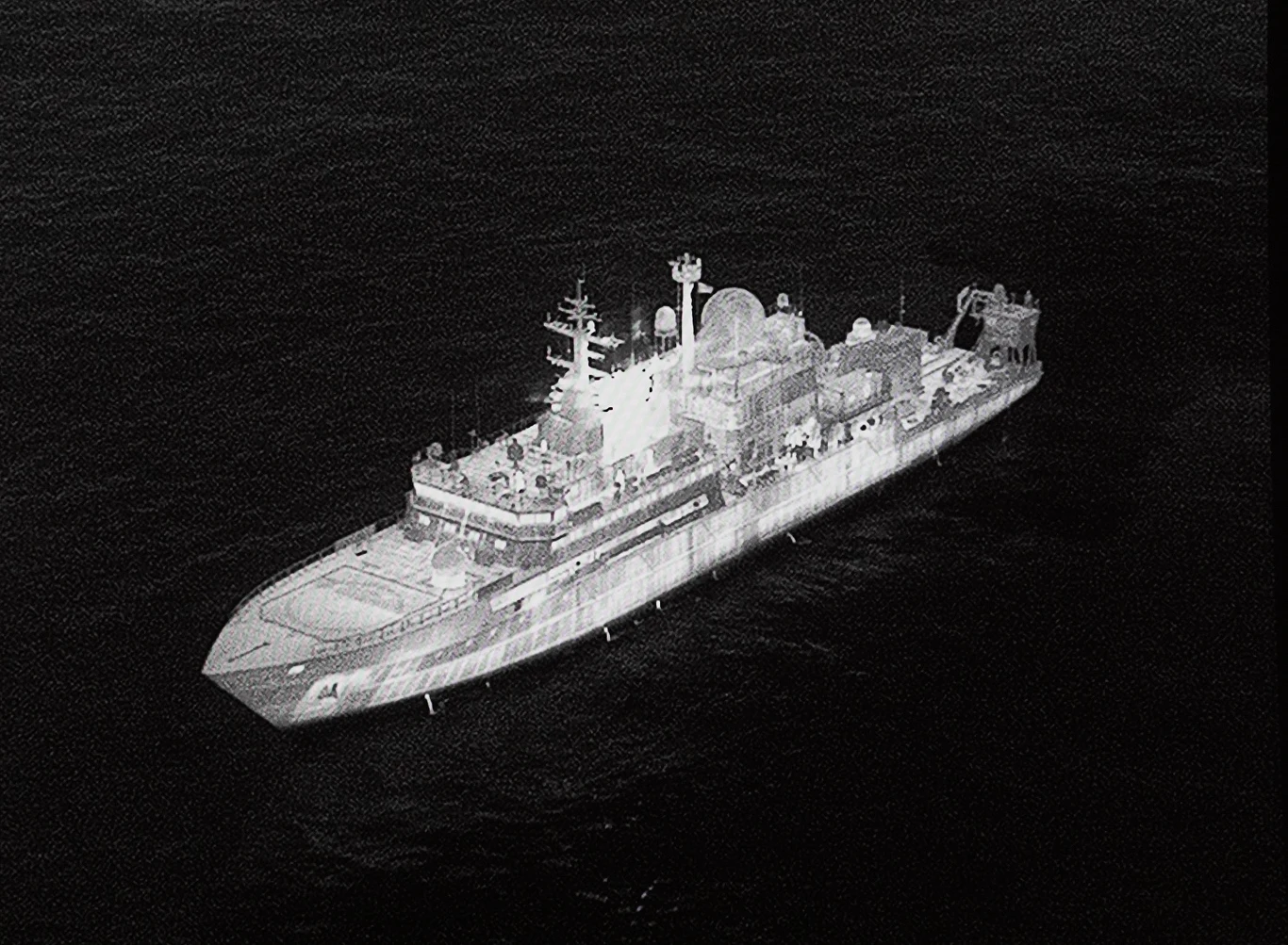 Rosyjski statek szpiegowski Jantar Duży okręt wojenny płynący po otwartym morzu, widoczna górna część pokładu z rozmaitymi konstrukcjami i wyposażeniem, statek otoczony ciemną wodą.