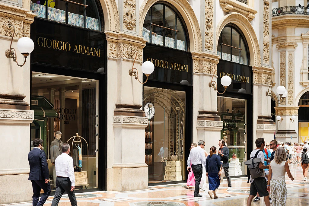 Rosjanie chętnie przyjeżdżają na zakupy do miast takich jak Mediolan Fasada eleganckiego butiku Giorgio Armani z charakterystycznymi czarnymi szyldami i złotymi literami, przez duże witryny widać wnętrze sklepu z luksusowymi produktami. Przed wejściem przechadzają się ludzie, niektórzy zatrzymują się, by obejrzeć ekspoz...