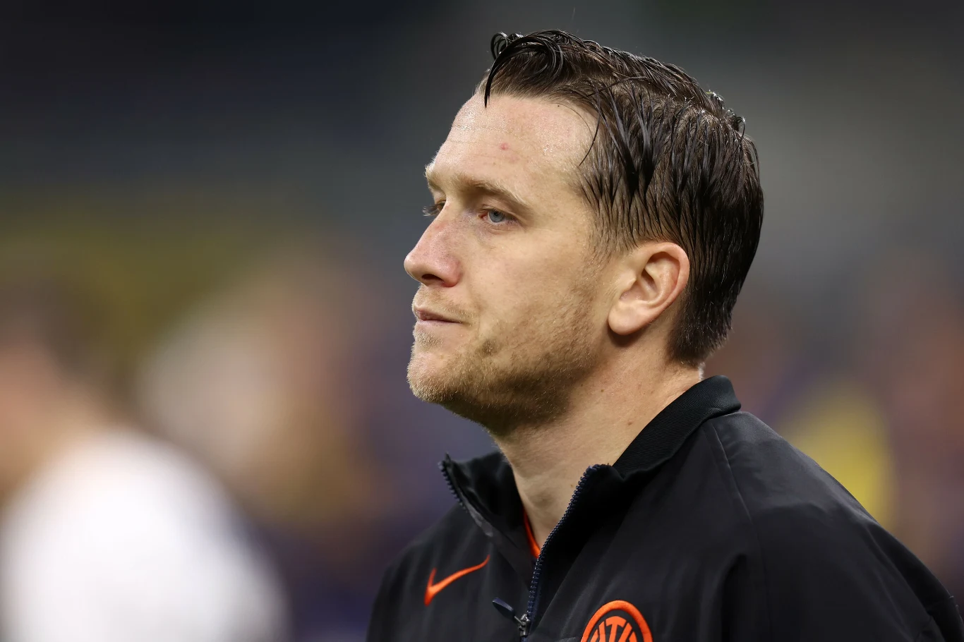 Piotr Zieliński Mężczyzna w sportowej kurtce z poważnym wyrazem twarzy, patrzący w bok. Tło rozmyte, skupienie na twarzy i górnej części sylwetki.