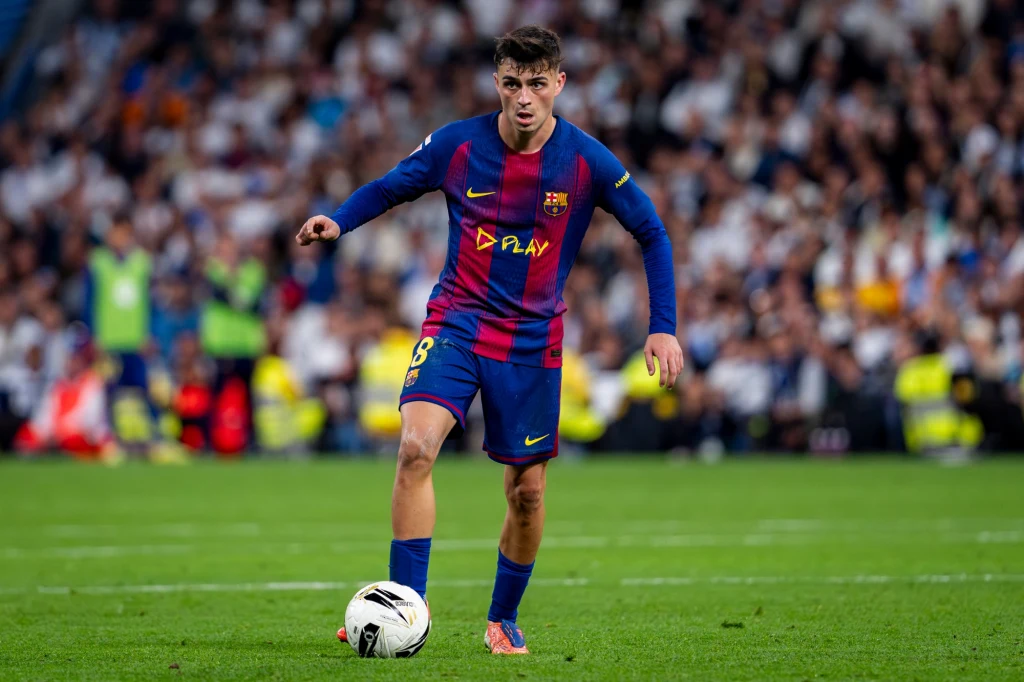 Piłkarz w stroju FC Barcelona kontroluje piłkę w trakcie meczu, w tle widoczna rozmyta publiczność stadionu.