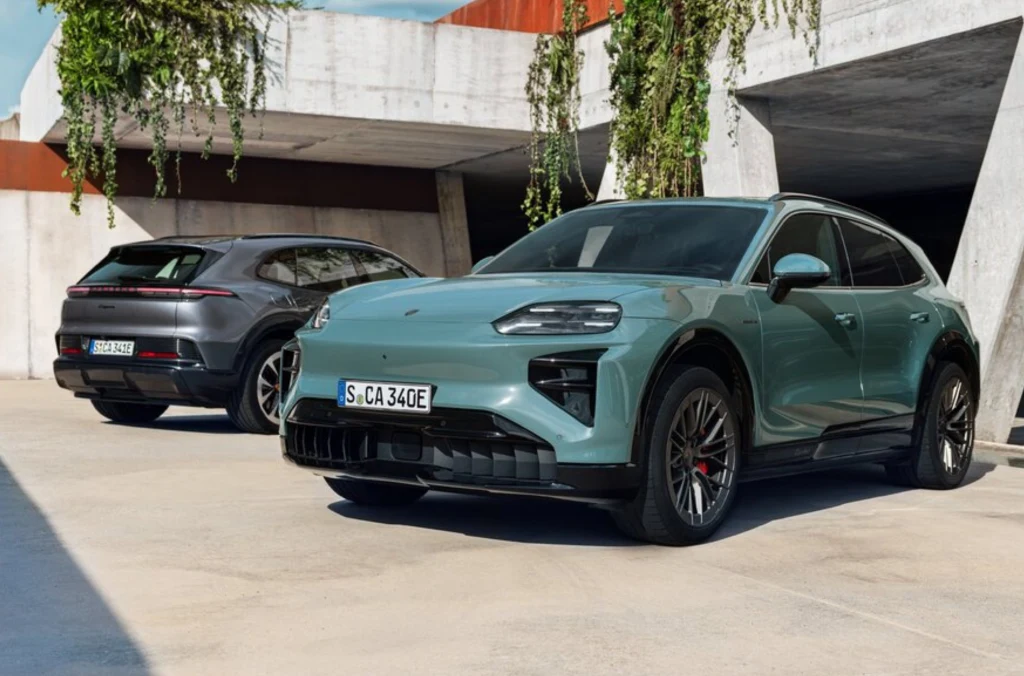 Dwa nowoczesne samochody elektryczne marki Porsche stojące na betonowym parkingu przy współczesnym budynku, z widoczną zielenią zwisającą z tarasu.