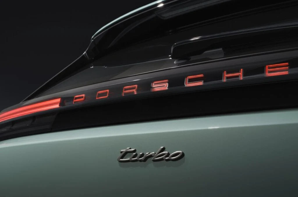 Tylny fragment samochodu sportowego z wyeksponowanym czerwonym podświetlanym napisem Porsche oraz chromowanym napisem turbo na zielonym lakierze.