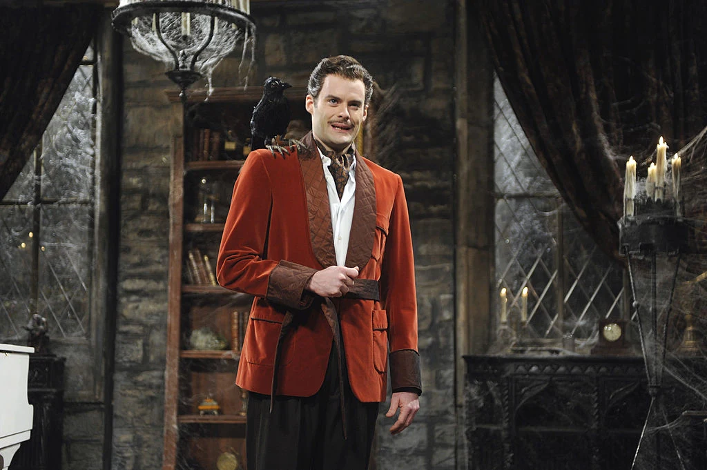 Mężczyzna w eleganckiej czerwonej marynarce z czarnym krukiem siedzącym na ramieniu, stojący w stylizowanym na gotycki wnętrzu z kamiennymi ścianami, zasłonami i świecami
