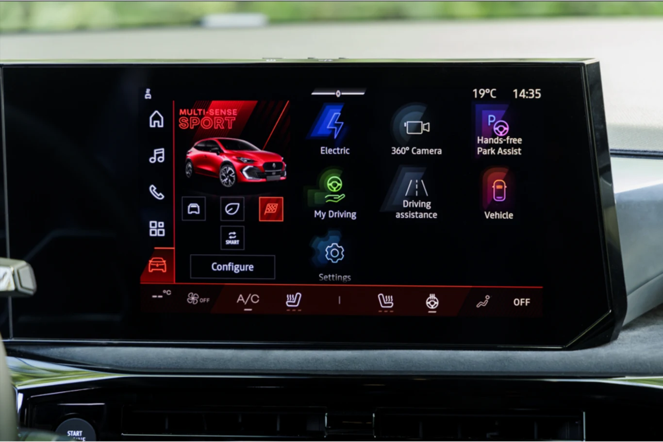 Ekran systemu multimedialnego samochodu z wyświetlonymi ikonami do wyboru trybów jazdy, asystentów wspomagania jazdy, kamery 360°, funkcji parkowania oraz ustawieniami pojazdu, temperatura i godzina wyświetlone w górnym rogu.