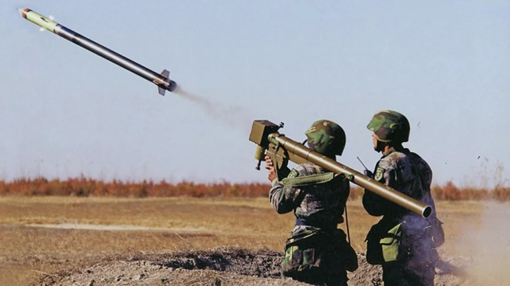 Dwóch żołnierzy w mundurach polowych wystrzeliwuje pocisk rakietowy z przenośnej wyrzutni, na tle otwartego terenu z suchą roślinnością.