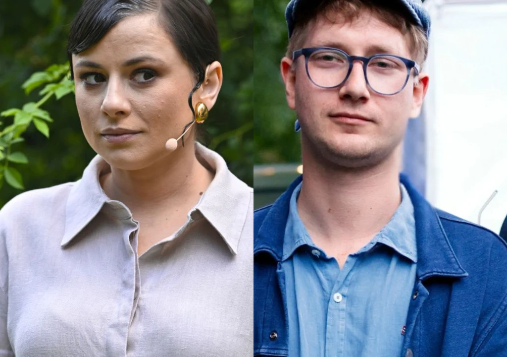 Dwie osoby ustawione obok siebie, kobieta z mikrofonem i mężczyzna w okularach i niebieskiej czapce. Kobieta ma upięte ciemne włosy, nosi jasną koszulę i przypięty do ucha mikrofon. Mężczyzna ma jasną cerę, jasne włosy, okulary oraz niebieską kurtkę na...