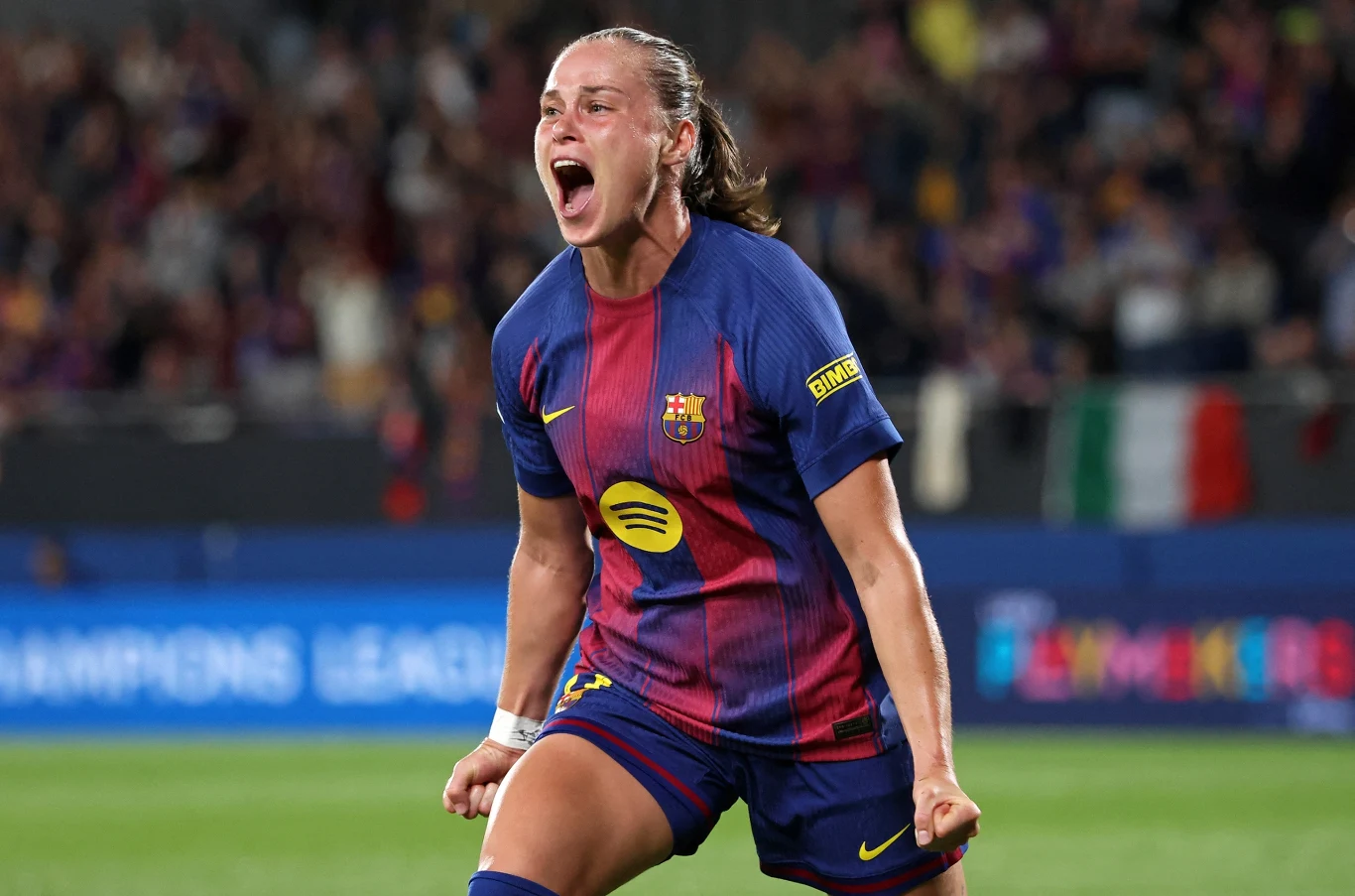 Ewa Pajor Piłkarka Barcelony w trakcie intensywnej celebracji, ubrana w klubowy strój, z uniesionymi pięściami i ekspresją radości na twarzy, na tle rozmytej publiczności stadionu.