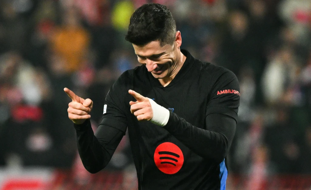 Robert Lewandowski przywitał w Barcelonie starego kumpla z Monachium Piłkarz w czarnym stroju z logo sponsora na piersi uśmiechnięty celebruje akcję, wskazując obiema dłońmi w bok. W tle rozmazana publiczność na stadionie.