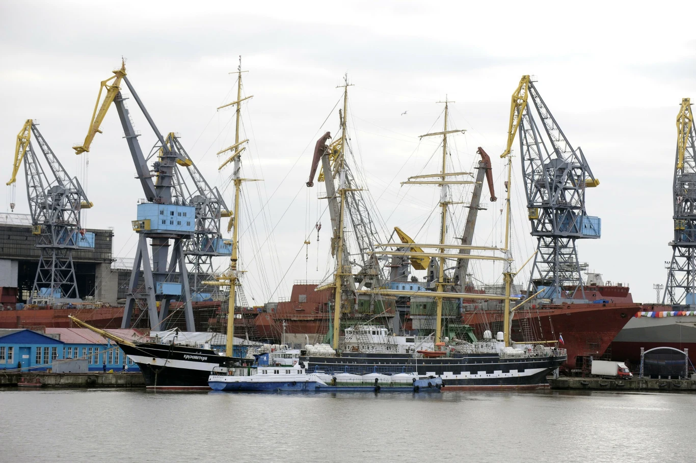 Rosyjska stocznia nie płaci pracownikom Port morski z dużą ilością dźwigów stoczniowych oraz kilkoma statkami, w tym żaglowcem i innymi jednostkami cumującymi przy nabrzeżu, w tle widoczne przemysłowe budynki stoczni.