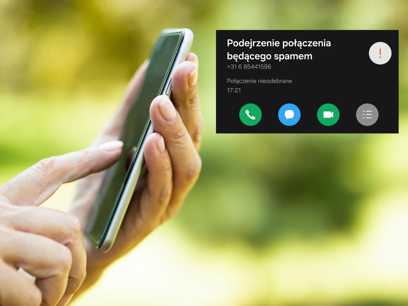 Do Polaków wydzwaniają nieznane numery. O co chodzi z połączeniami z kierunkowego +31? Osoba trzymająca smartfon w dłoni na tle zielonego, rozmytego otoczenia, a na ekranie telefonu powiadomienie o nieodebranym połączeniu uznanym za potencjalny spam.