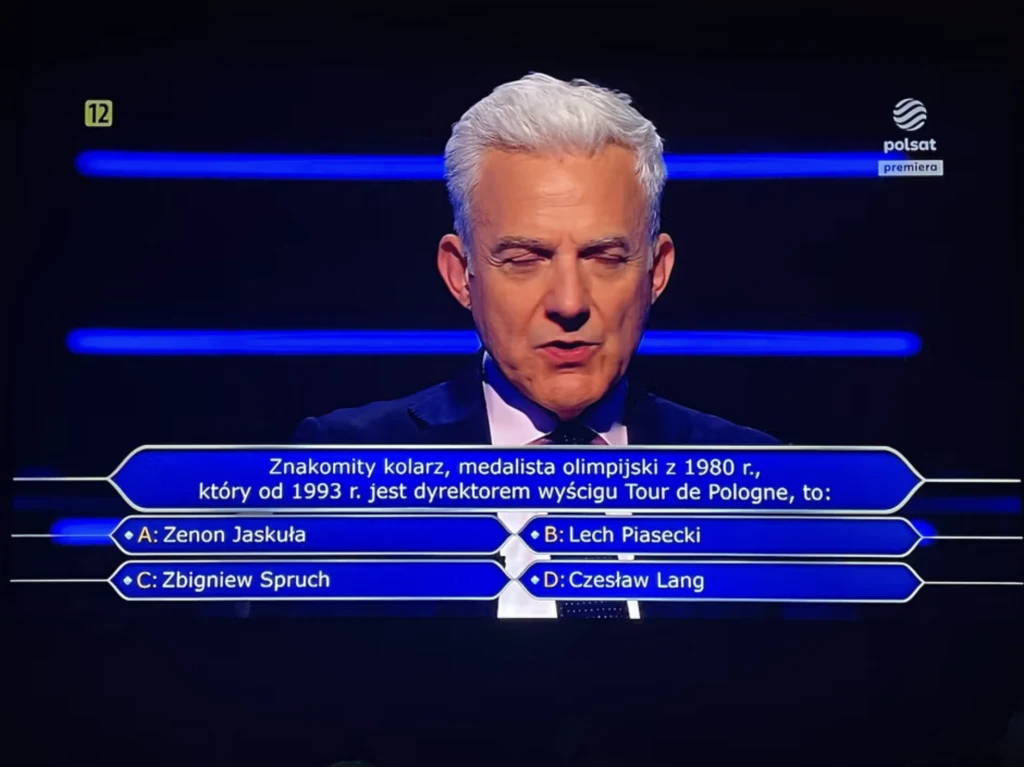 W "Milionerach" padło pytanie o polskie kolarstwo Mężczyzna o siwych włosach prowadzi teleturniej, podczas którego na ekranie pojawia się pytanie dotyczące znakomitego kolarza oraz cztery możliwe odpowiedzi oznaczone literami od A do D. W tle widoczne niebieskie światła oraz logo stacji Polsat.