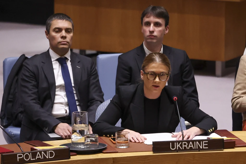 Wojna w Ukrainie. Ukraina jest gotowa do rozmów z Rosją, ale stawia warunki Delegacja Ukrainy przemawia podczas oficjalnego posiedzenia międzynarodowej organizacji, obok widoczny przedstawiciel Polski. Mówiąca kobieta siedzi za mikrofonem, przed nią dokumenty i karafka z wodą.