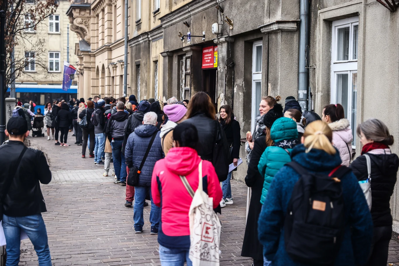 Brytyjski "Daily Express" uznał Kraków za najlepszy i najtańszy kierunek na krótki wyjazd między świętami a sylwestrem Długa kolejka ludzi ustawionych wzdłuż chodnika przy budynku urzędu miejskiego, większość osób ubrana w ciepłą odzież, niektóre z plecakami i torbami, atmosfera wyczekiwania