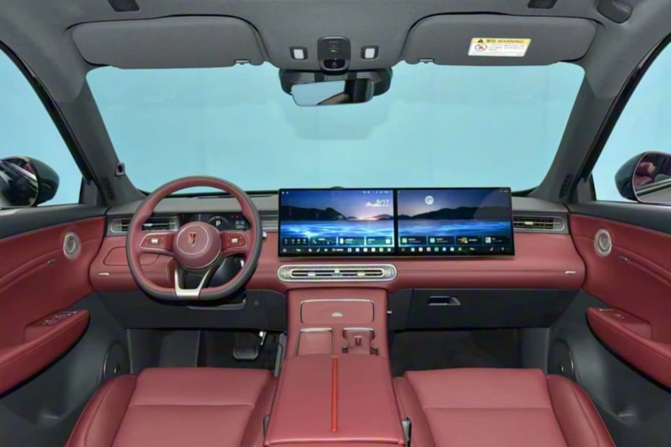 System multimedialny Hongqi HS6 składa się z dwóch ekranów Luksusowe wnętrze nowoczesnego samochodu z czerwonym wykończeniem skórzanym, dwoma dużymi ekranami dotykowymi na konsoli środkowej oraz wielofunkcyjną kierownicą.