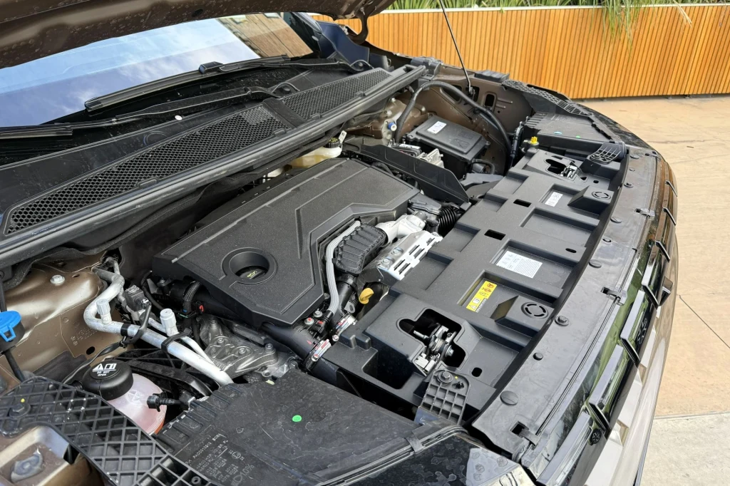 Jeep Compass wyposażony jest w trzycylindrowy silnik benzynowy o pojemności 1,2 l. To najmniejsza jednostka w historii tego modelu. Komora silnika samochodu z widocznymi przewodami, plastikowymi osłonami i elementami technicznymi, na pierwszym planie czysta jednostka napędowa.