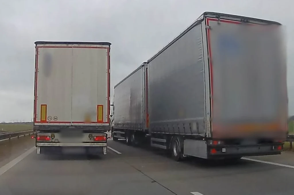 Policjanci z Belgii wzięli na tapet "wyścigi słoni". Z powietrza wykroczenia wychwytywał helikopter. Dwa duże samochody ciężarowe jadą równolegle dwoma pasami w jednym kierunku na autostradzie, otoczenie stanowi droga i pola po obu stronach jezdni, niebo zachmurzone.