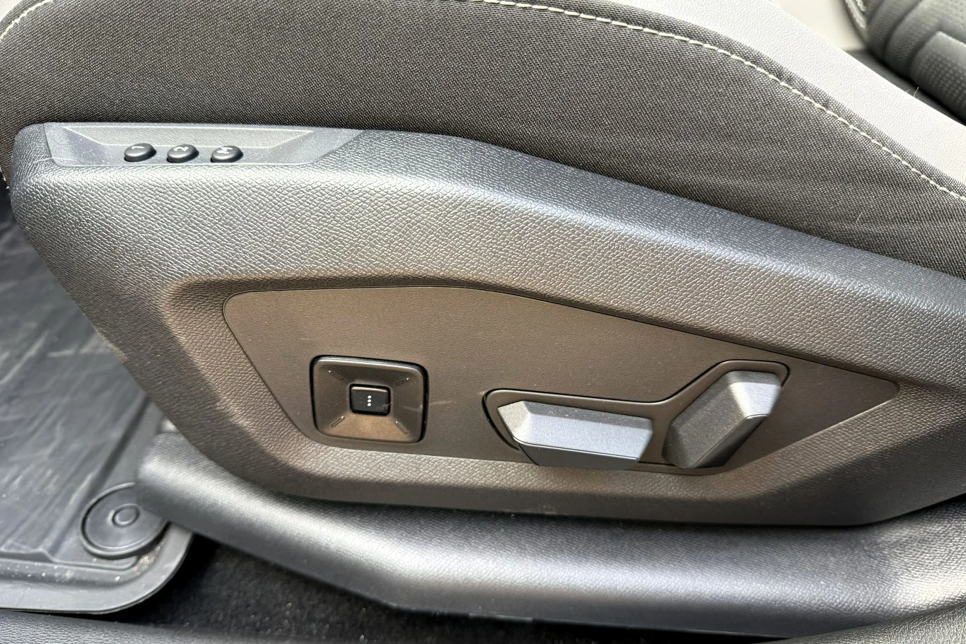 Panel sterowania elektrycznego fotela samochodowego z widocznymi przyciskami i przełącznikami umożliwiającymi regulację pozycji siedzenia.