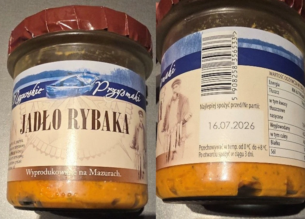 Słoik z czerwonym wieczkiem zawierający produkt spożywczy o nazwie Jadło Rybaka. Etykieta z niebieskimi i beżowymi elementami, nadrukowana ryba, obrazek rybaka oraz informacja o wartości odżywczej, data ważności i kod kreskowy.