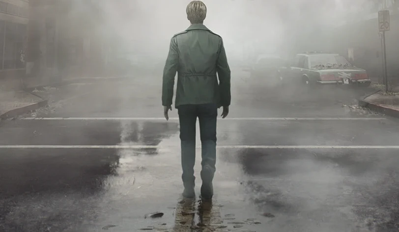 Silent Hill 2 Remake Postać mężczyzny w zielonej kurtce odwrócona tyłem, idzie ulicą pokrytą kałużami, wokół gęsta mgła utrudniająca widoczność; po bokach w oddali stoją samochody.