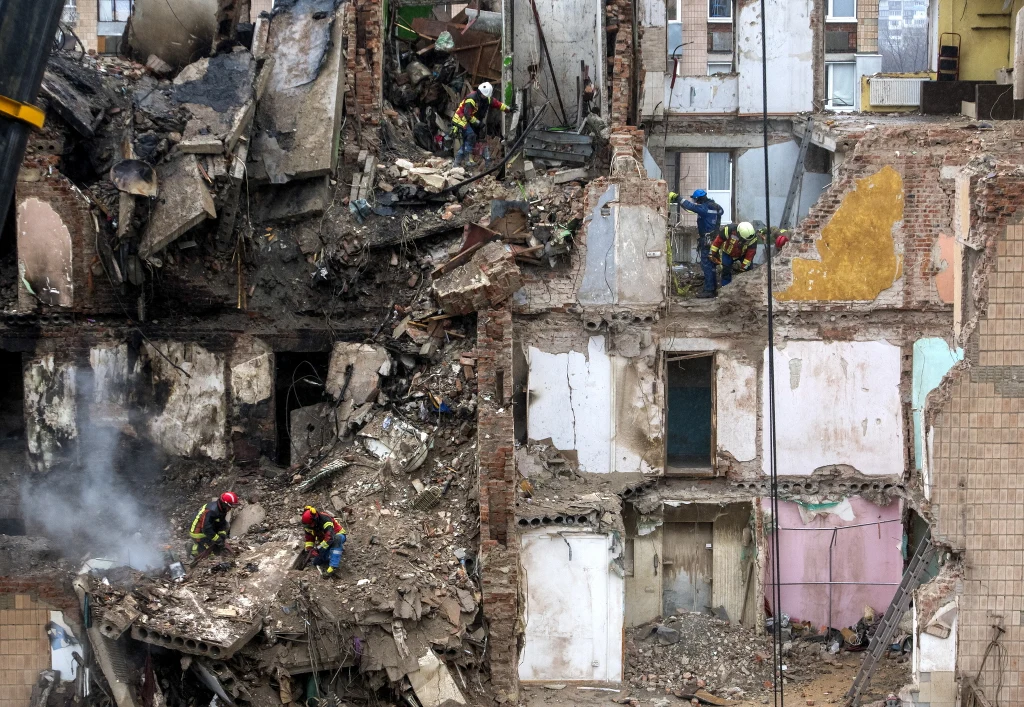 Zniszczenia po rosyjskim ataku w Tarnopolu Strażacy przeszukują gruzowisko zniszczonego, zawalonego budynku mieszkalnego. Widoczne liczne poważne uszkodzenia ścian, odsłonięte wnętrza mieszkań oraz porozrzucane fragmenty konstrukcji.