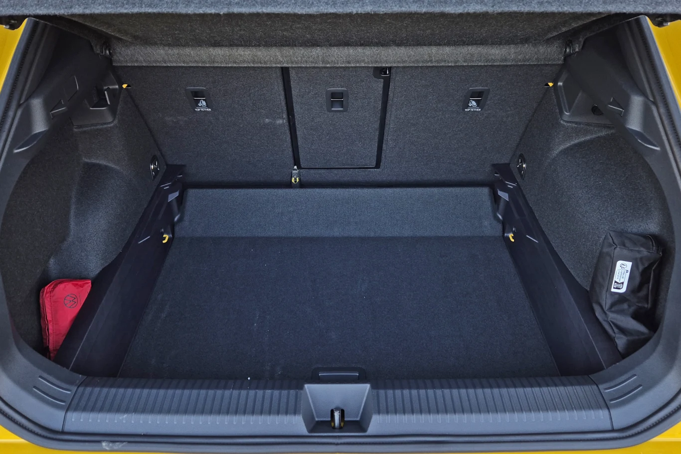 Volkswagen T-Roc ma bagażnik o pojemności 475 l, ale wlicza się w to przestrzeń widoczna po opuszczeniu podłogi Pojemny bagażnik samochodu osobowego o prostokątnym kształcie, z czarną wykładziną, miejscem na drobne akcesoria po bokach oraz złożonymi tylnymi siedzeniami.