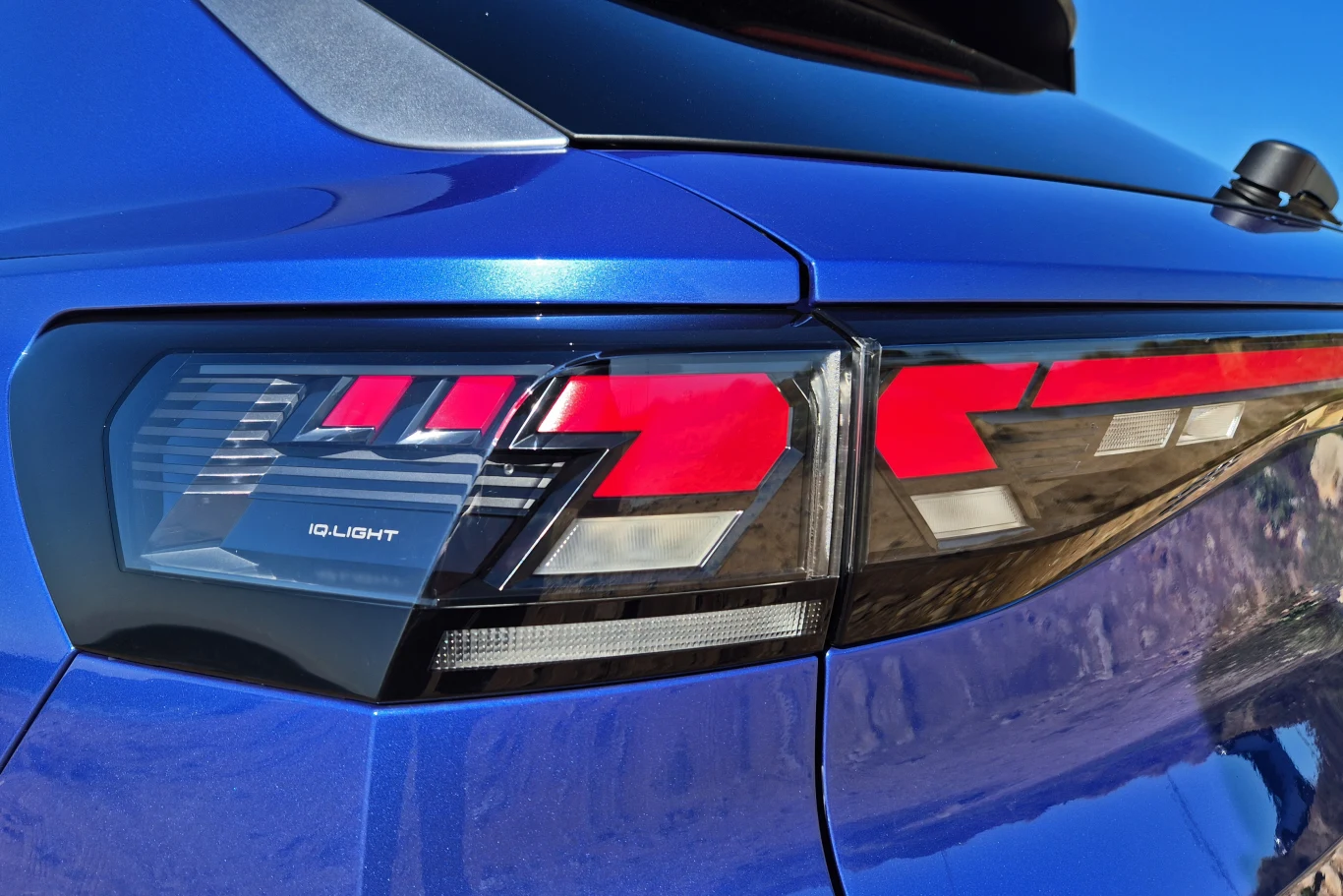 Volkswagen T-Roc Tylna lampa samochodu z nowoczesnym wzorem świateł LED i oznaczeniem IQ.LIGHT na niebieskim lakierze karoserii.