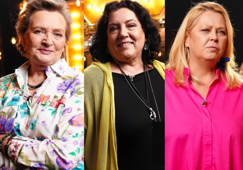 Trzy dorosłe kobiety ustawione obok siebie, każda patrzy w stronę obiektywu. Kobieta po lewej ma na sobie kolorową koszulę w kwiaty, środkowa ubrana jest w czarną bluzkę i żółty sweter, a kobieta po prawej ma różową koszulę. Wszystkie stoją na tle ciem...