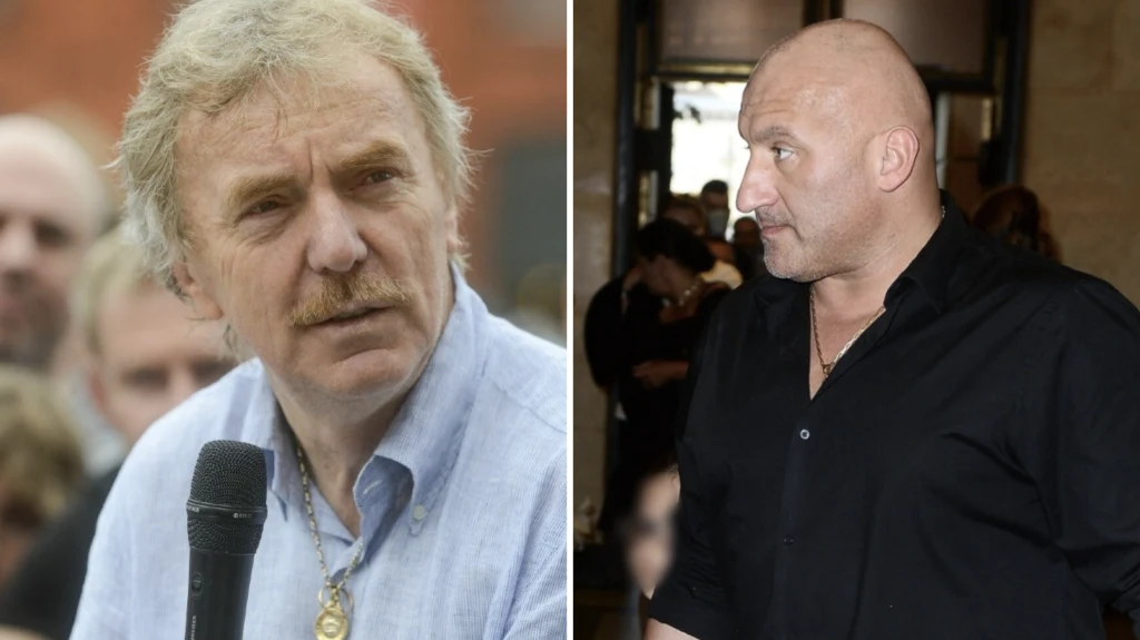 Zbigniew Boniek, Marcin Najman Po lewej stronie mężczyzna z mikrofonem w dłoni, blond włosy i wąsy, ubrany w jasną koszulę z naszyjnikiem na szyi, w tle rozmyta grupa ludzi. Po prawej łysy mężczyzna w czarnej koszuli, zaciśnięte usta i stanowczy wyraz twarzy, w tle nieostre wnętrze ...