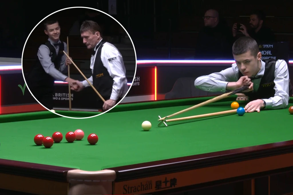 Zawodnik skupiony podczas rozgrywki w snookera celuje kijem w białą bilę, korzystając z przedłużenia, podczas gdy drugi zawodnik stoi obok stołu. W kółku widoczny moment uścisku dłoni między graczami.