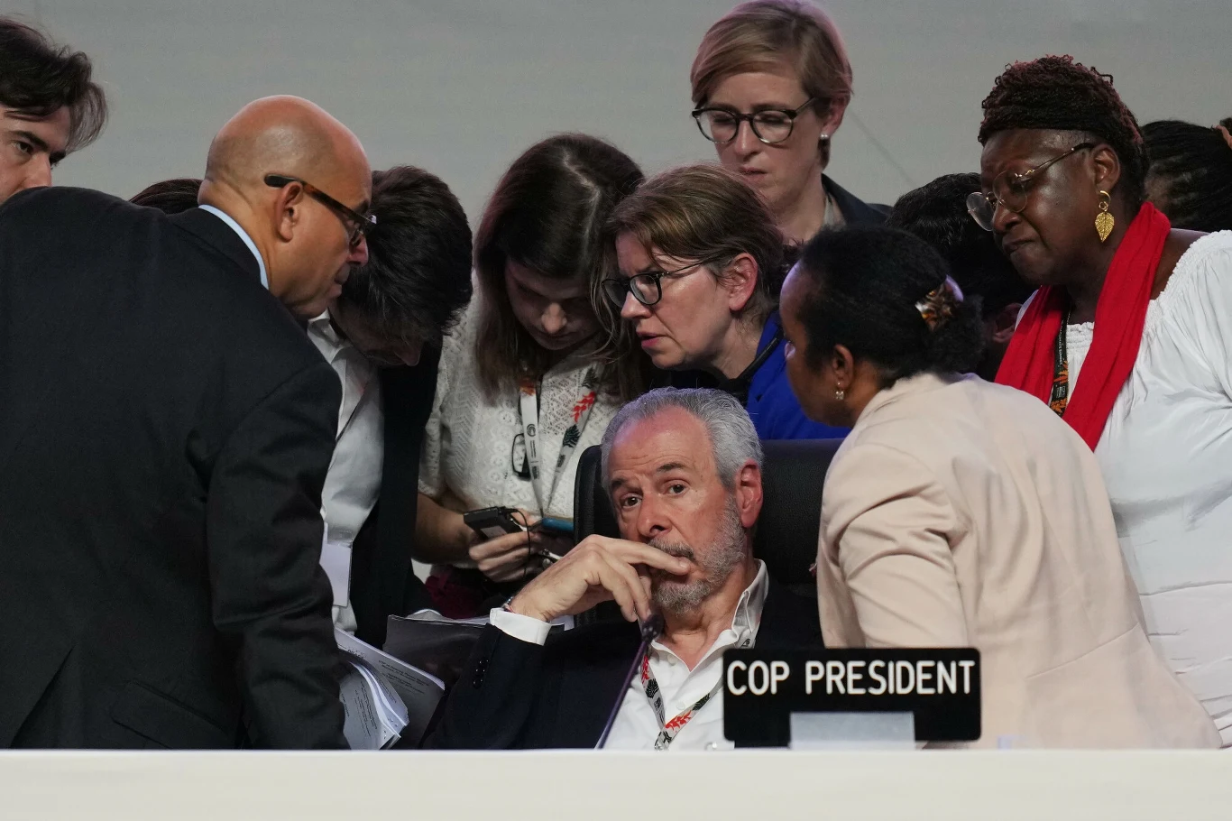 Dyskusje na szczycie COP30 w Belem były niełatwe Grupa osób intensywnie dyskutujących przy stole konferencyjnym, w centrum uwagi siedzi mężczyzna oznaczony jako prezydent COP, wokół niego zgromadzona jest kilkuosobowa grupa współpracowników pochylających się i analizujących ważne dokumenty.