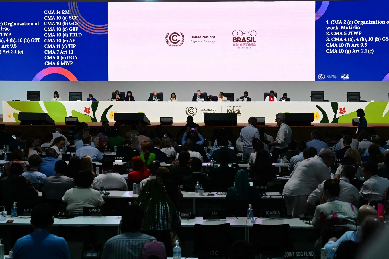 Obrady szczytu COP30 w Belem Konferencja klimatyczna, sala wypełniona delegatami siedzącymi przy stołach, na podwyższeniu długa ława z przedstawicielami organizatorów na tle dużego ekranu z logotypami Konferencji Narodów Zjednoczonych w sprawie zmian klimatu oraz COP30 Brasil. Prz...
