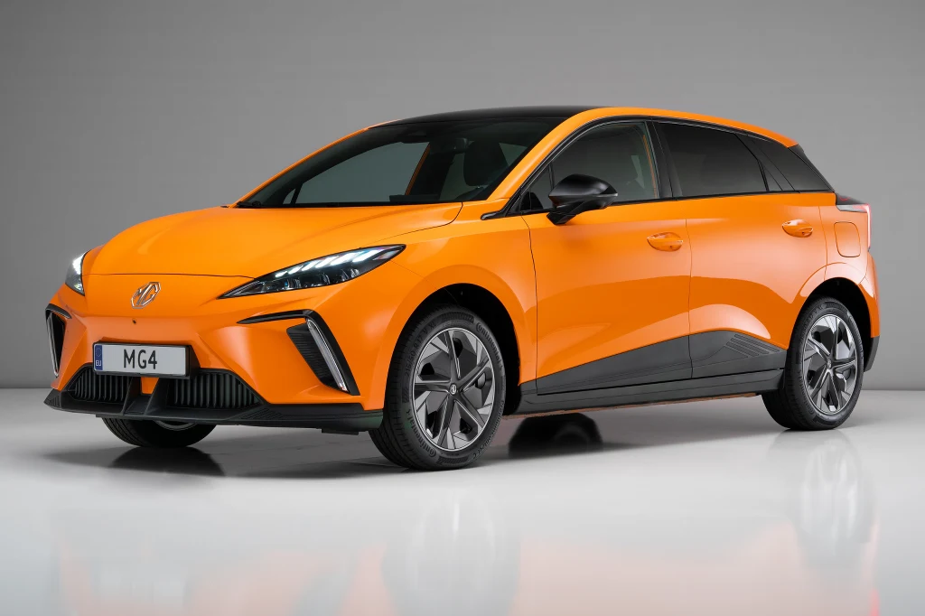 MG4 to najbardziej awaryjny samochód elektryczny w rankingu Pomarańczowy samochód osobowy MG4 o nowoczesnym designie i dynamicznych liniach karoserii, stoi na jasnym tle studyjnym. Wyraźne reflektory LED, czarne elementy nadwozia oraz stylizowane felgi podkreślają sportowy charakter pojazdu.