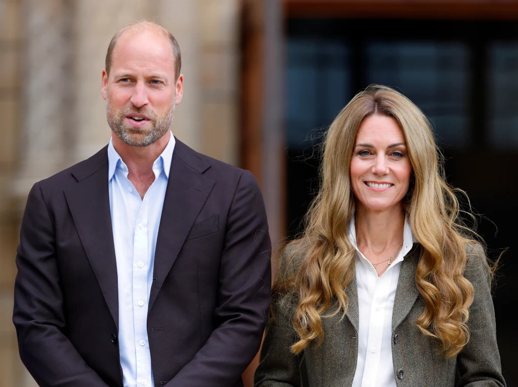 Miodowe loki księżnej Kate wywołały niemałą burzę we wrześniu 2025 roku Mężczyzna w ciemnej marynarce, stojący obok kobiety z długimi, falowanymi włosami, ubranej w białą koszulę i marynarkę, oboje uśmiechnięci, w tle niewyraźna architektura.