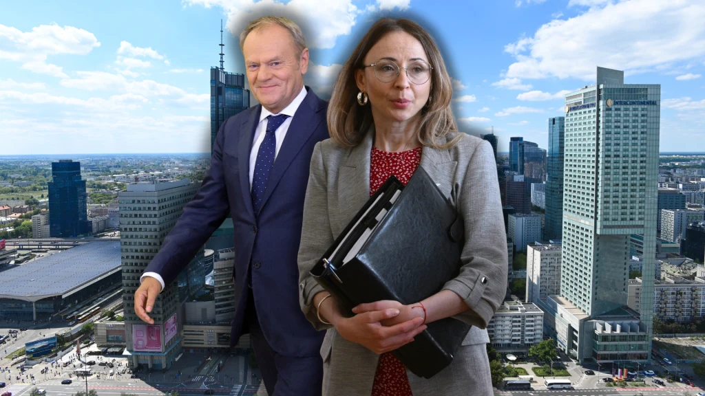 Dwie osoby w stroju biznesowym na tle panoramy nowoczesnego miasta z wysokimi wieżowcami i przeszklonymi budynkami; kobieta trzyma dokumenty i segregator.