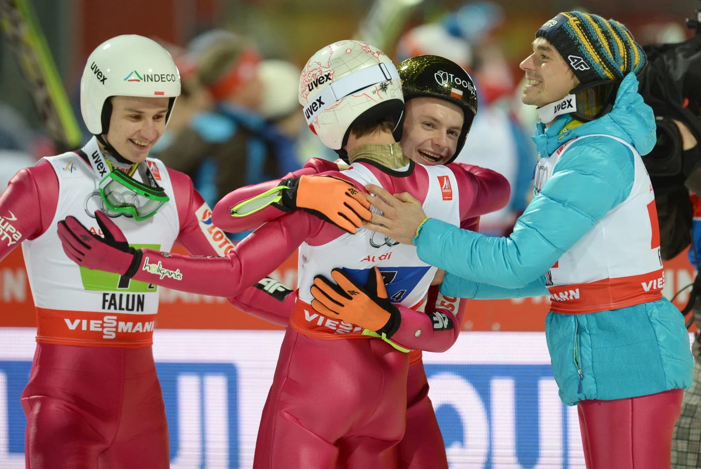 Radość Polaków po medalu MŚ w Falun. Od lewej: Klemens Murańka, Kamil Stoch Ityłem), Jan Ziobro i Piotr Żyła Grupa sportowców w kombinezonach narciarskich celebruje sukces, obejmując się oraz wyrażając radość po zawodach skoków narciarskich; widoczne kaski, numery startowe oraz elementy sprzętu narciarskiego.