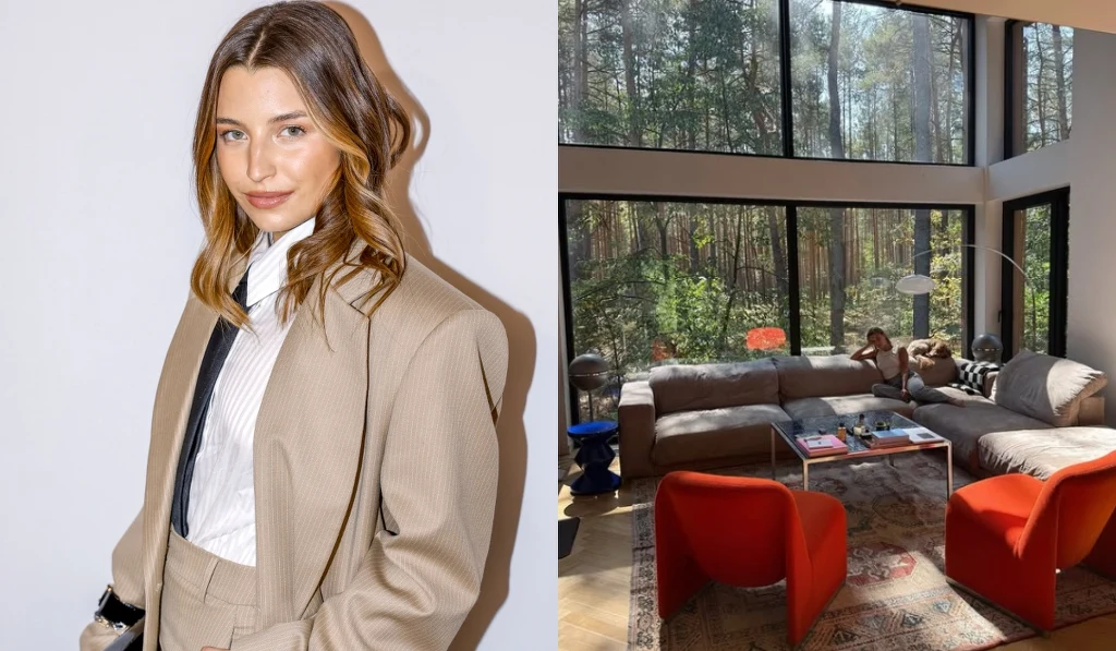 Młoda kobieta w eleganckim, beżowym garniturze stoi na jasnym tle. Obok nowoczesny salon z dużymi oknami, przez które widać las, wyposażony w wygodny narożnik, czerwone fotele i stolik kawowy. Wnętrze jest przestronne i pełne naturalnego światła.