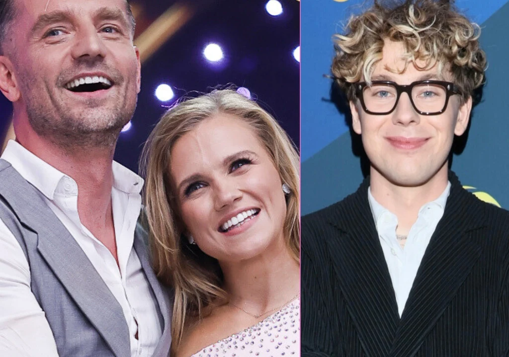 Dwie uśmiechnięte osoby w eleganckich strojach stoją blisko siebie na tle kolorowych świateł oraz młody mężczyzna w okularach i marynarce na niebieskim tle.