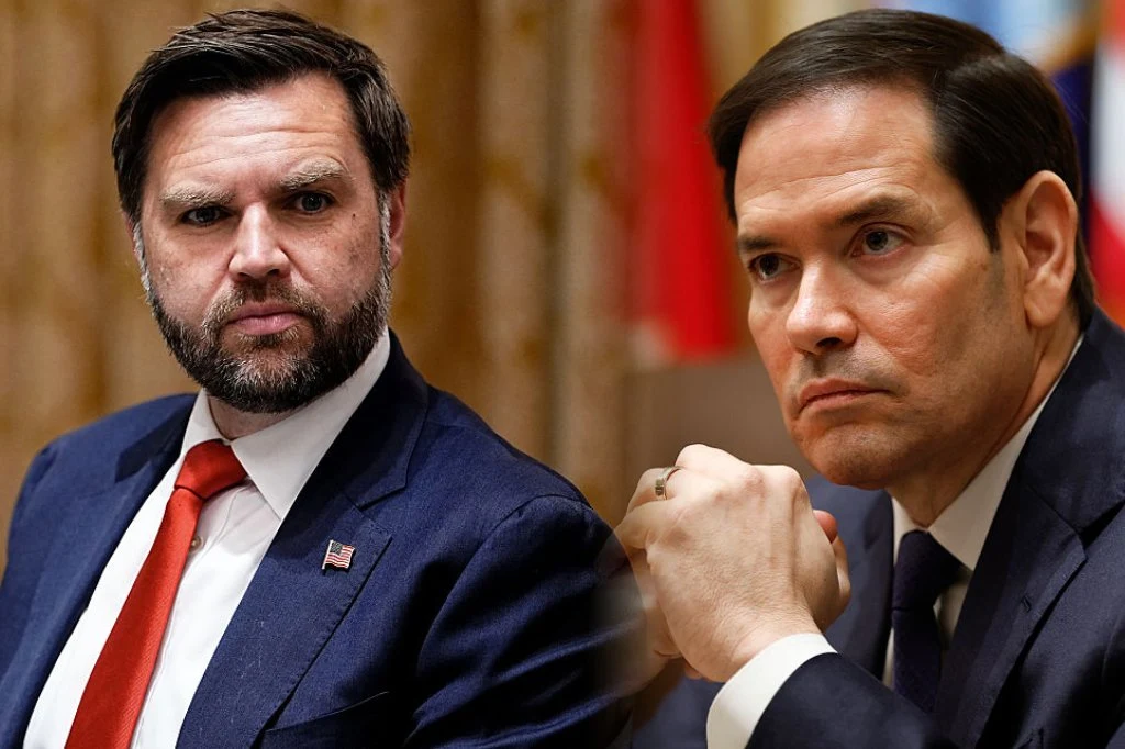 Dwóch mężczyzn w garniturach znajduje się w formalnym otoczeniu, jeden patrzy bezpośrednio przed siebie, drugi wspiera brodę na dłoni i spogląda w bok. W tle widoczne rozmyte flagi.