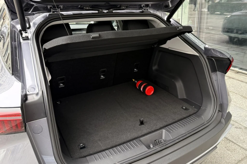 Otwarty bagażnik samochodu osobowego z umieszczoną po prawej stronie gaśnicą, wnętrze czyste i przestronne, widoczne oparcia tylnej kanapy.