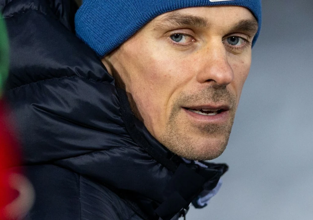 Mężczyzna w niebieskiej czapce i ciemnej kurtce patrzy w bok, twarz z widocznymi detalami, neutralne tło.