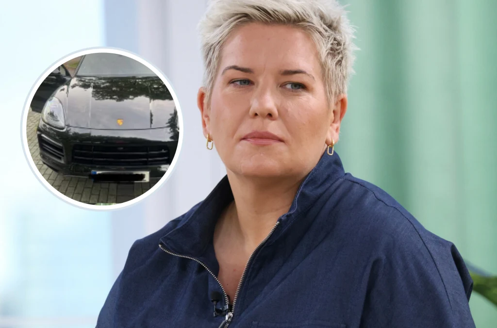 Anita Włodarczyk sprzedaje Porsche Cayenne. Auto ma 43 tys. km przebiegu. Kobieta o krótkich blond włosach patrzy przed siebie, ubrana w granatową kurtkę, a na pierwszym planie znajduje się powiększone koło z wizerunkiem czarnego samochodu marki Porsche.