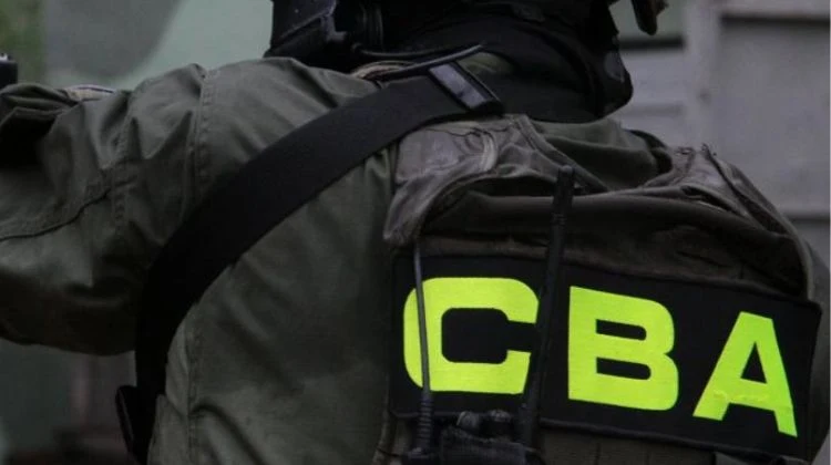 Agenci CBA weszli do siedziby fundacji ojca Rydzyka Funkcjonariusz ubrany w mundur taktyczny, z dużym, wyraźnym napisem CBA na plecach, wyposażony w hełm ochronny i kamizelkę, widoczny od tyłu podczas akcji lub przygotowań do działań służbowych.