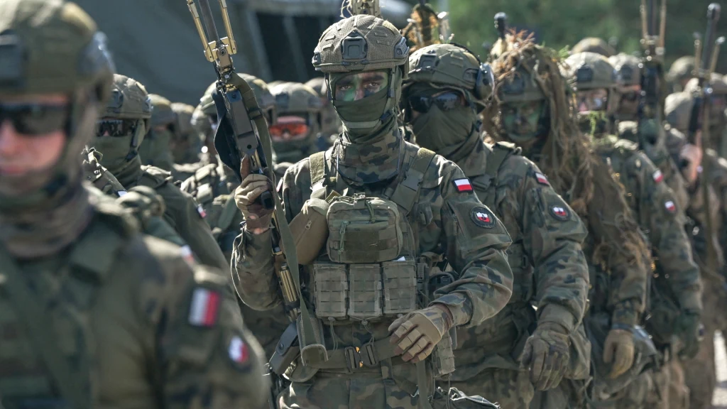 44 miliardy euro na polską armię. 89% tej kwoty ma wesprzeć polskie firmy Oddział żołnierzy w pełnym umundurowaniu i uzbrojeniu, każdy nosi kamizelkę taktyczną, hełm i maskę, na ramionach widoczne polskie flagi, tło zamazane, skupienie na centralnych postaciach. Wszystkie twarze zamaskowane, żołnierze stoją w rzędzie.